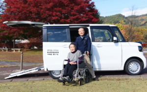 車椅子も乗り入れ可能なNPO法人スマイルニ使用の車を前に、お客様と稲尾さん